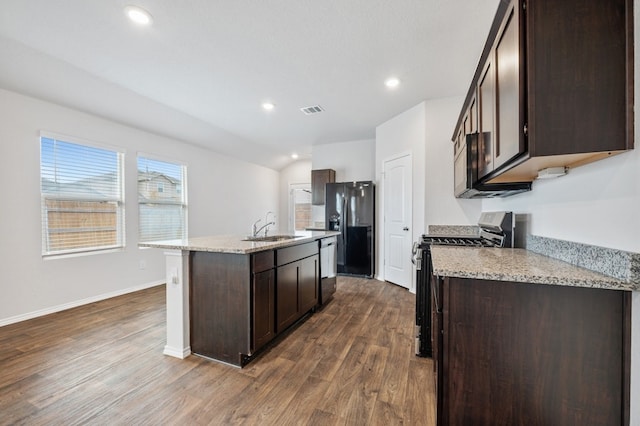kitchen with stainless steel gas range, black fridge with ice dispenser, visible vents, and dark brown cabinetry