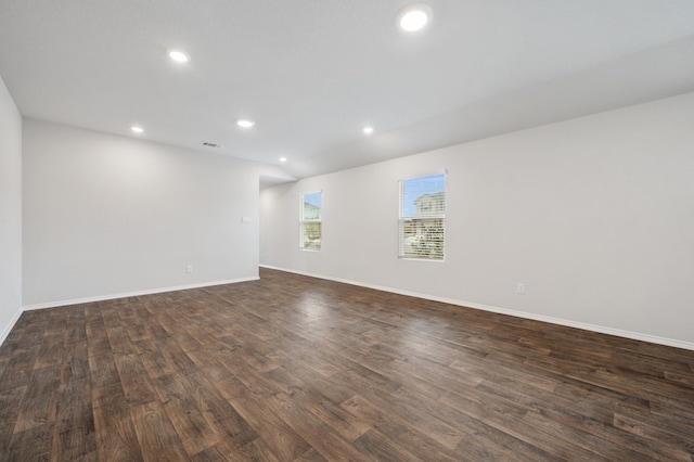 empty room featuring dark wood-type flooring, visible vents, baseboards, and recessed lighting