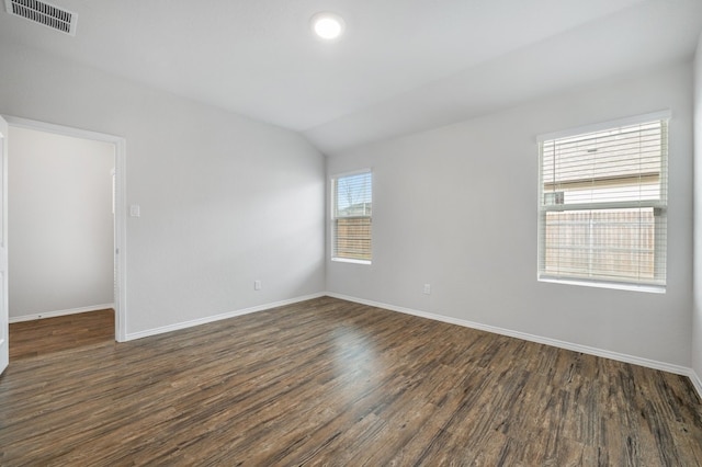 empty room featuring dark wood finished floors, baseboards, visible vents, and lofted ceiling