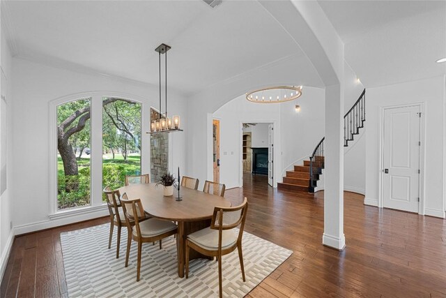3416 Tarlton Ln, Austin, TX 78746 - dining room featuring a chandelier, wood-type flooring, stairs, arched walkways, and baseboards
