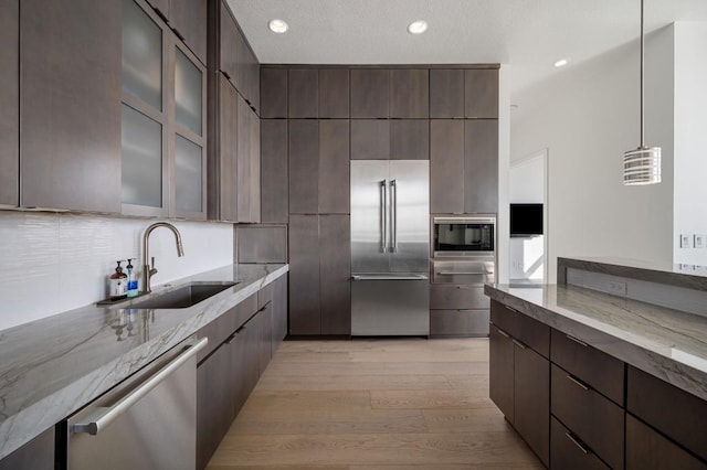 555 E 5th St Unit 2906, Austin, TX 78701 - kitchen with built in appliances, modern cabinets, light wood-type flooring, light stone counters, and dark brown cabinets