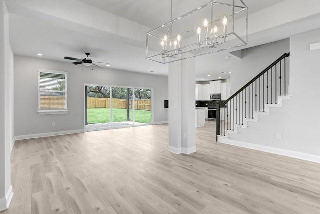 unfurnished living room with recessed lighting, light wood-style floors, baseboards, and ceiling fan with notable chandelier