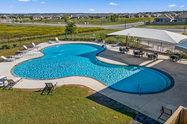 community pool featuring a patio area, a lawn, and fence