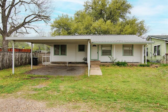 1116-C Simpson St, Schulenburg, TX 78956 - view of front of home featuring metal roof, fence, an attached carport, a front lawn, and driveway