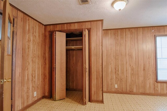 1116-C Simpson St, Schulenburg, TX 78956 - unfurnished bedroom featuring wood walls, light floors, a textured ceiling, baseboards, and visible vents