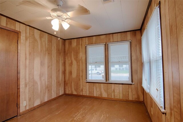 1116-C Simpson St, Schulenburg, TX 78956 - empty room featuring crown molding, a ceiling fan, wooden walls, wood finished floors, and baseboards