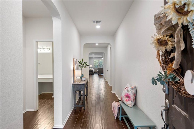 hall with visible vents, baseboards, arched walkways, dark wood-style flooring, and recessed lighting
