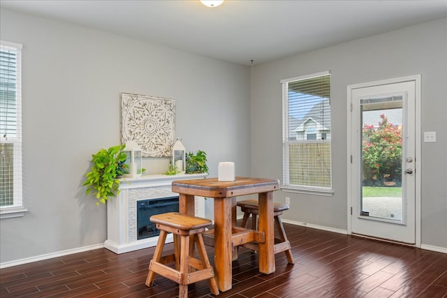 dining area with baseboards, dark wood-style flooring, and a fireplace