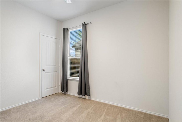 unfurnished room featuring light carpet and baseboards