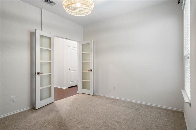 unfurnished bedroom featuring an inviting chandelier, french doors, carpet, baseboards, and visible vents