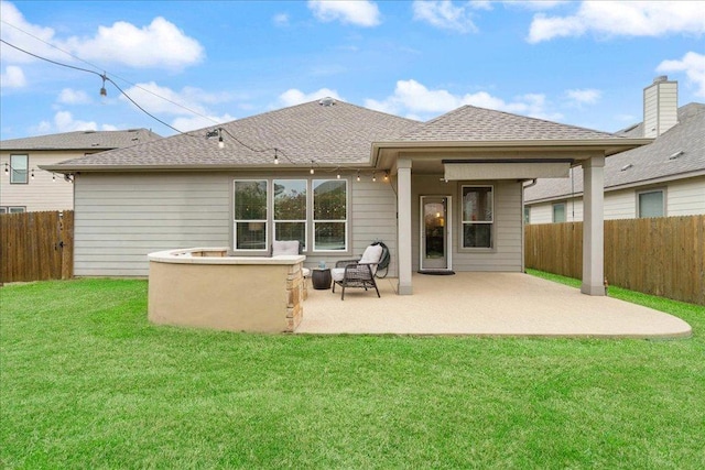 back of house with fence, a lawn, a shingled roof, and a patio area