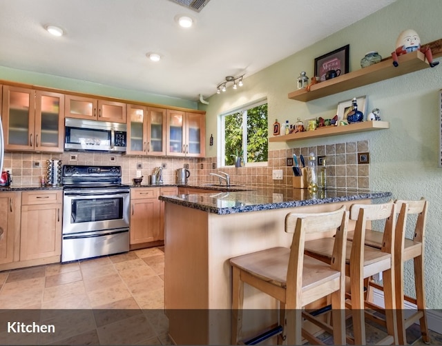kitchen featuring decorative backsplash, appliances with stainless steel finishes, and a peninsula