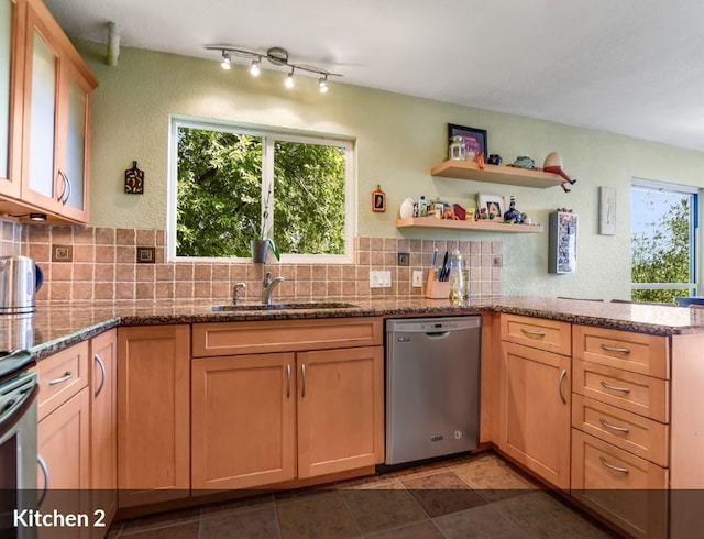 kitchen featuring a sink, stone countertops, a peninsula, stainless steel dishwasher, and decorative backsplash