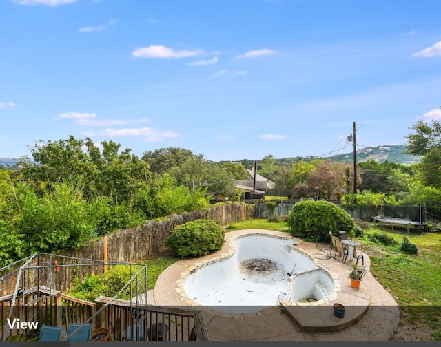 view of pool with a trampoline, a fenced backyard, and a patio