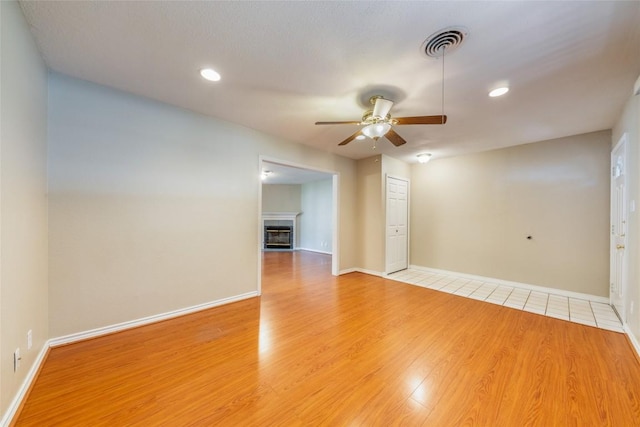 2004 Teakwood Dr, Austin, TX 78757 - empty room with ceiling fan, light wood-style flooring, a glass covered fireplace, and recessed lighting