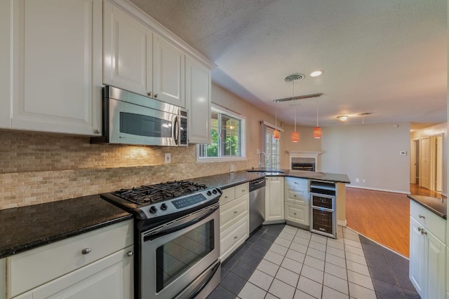 2004 Teakwood Dr, Austin, TX 78757 - kitchen featuring appliances with stainless steel finishes, wine cooler, tile patterned flooring, a peninsula, and decorative backsplash