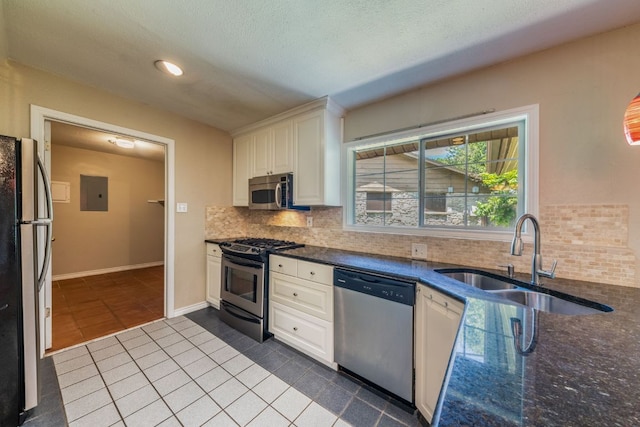 2004 Teakwood Dr, Austin, TX 78757 - kitchen with appliances with stainless steel finishes, dark tile patterned flooring, electric panel, backsplash, and white cabinetry