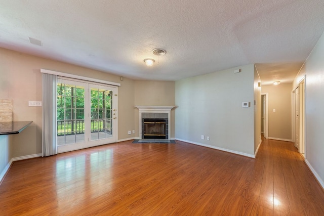 2004 Teakwood Dr, Austin, TX 78757 - unfurnished living room with wood finished floors, a tile fireplace, and a textured ceiling