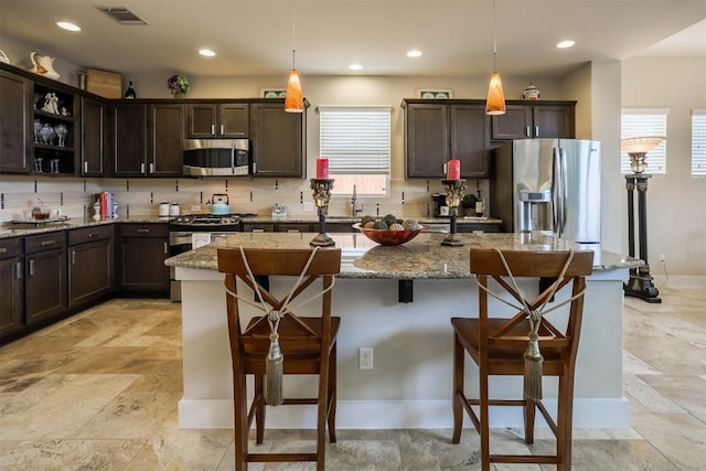 11913 Natures Bnd, Austin, TX 78753 - kitchen with stainless steel appliances, dark brown cabinetry, a kitchen bar, and recessed lighting