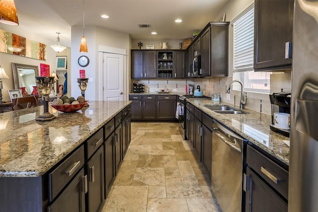 11913 Natures Bnd, Austin, TX 78753 - kitchen featuring stainless steel appliances, stone tile floors, dark brown cabinets, decorative backsplash, and light stone countertops