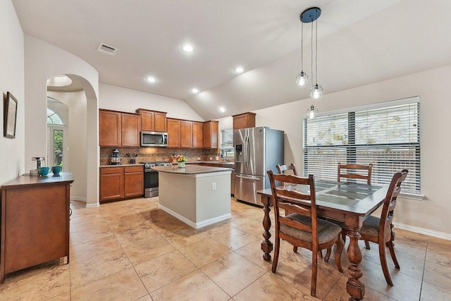 1411 Rowan Dr, Georgetown, TX 78628 - kitchen with appliances with stainless steel finishes, lofted ceiling, brown cabinets, tasteful backsplash, and a kitchen island