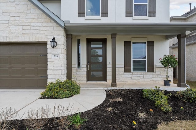 708 Leeward Pass, Leander, TX 78641 - view of exterior entry featuring stone siding, covered porch, stucco siding, and a garage