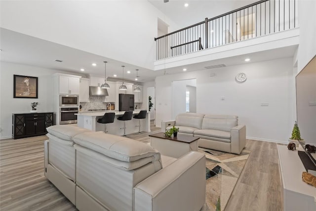 708 Leeward Pass, Leander, TX 78641 - living room featuring light wood-style floors, a towering ceiling, and recessed lighting