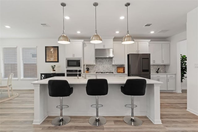 708 Leeward Pass, Leander, TX 78641 - kitchen with refrigerator, under cabinet range hood, black microwave, light countertops, and white cabinets