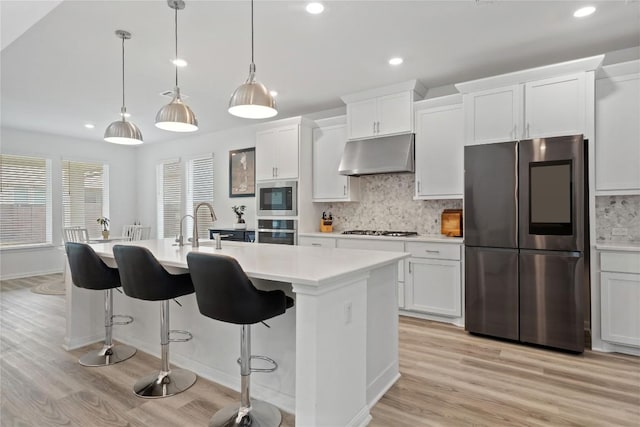 708 Leeward Pass, Leander, TX 78641 - kitchen featuring appliances with stainless steel finishes, under cabinet range hood, light wood-style floors, light countertops, and recessed lighting