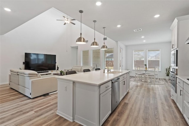 708 Leeward Pass, Leander, TX 78641 - kitchen featuring appliances with stainless steel finishes, open floor plan, light wood-style flooring, light countertops, and an island with sink