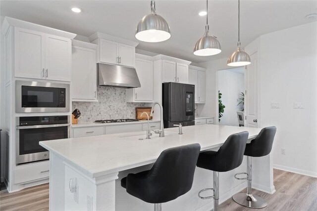 708 Leeward Pass, Leander, TX 78641 - kitchen featuring stainless steel appliances, under cabinet range hood, light wood-style flooring, light countertops, and recessed lighting