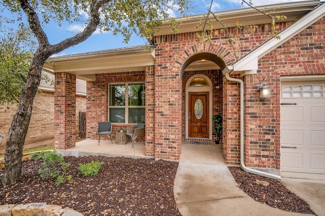 property entrance featuring an attached garage and brick siding
