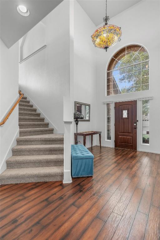foyer entrance with stairs, wood-type flooring, and a towering ceiling