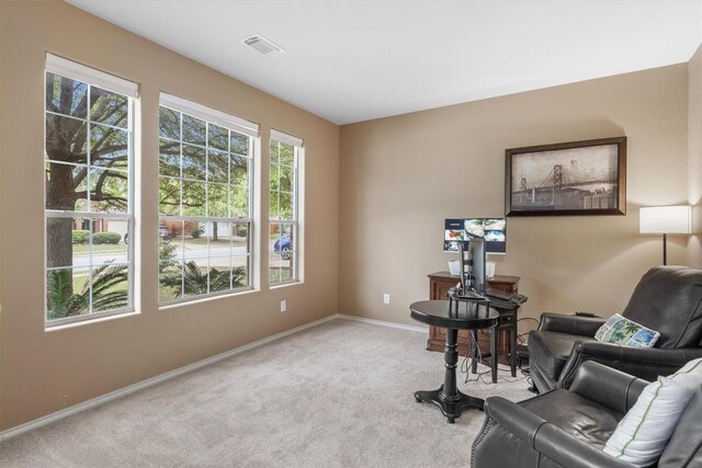 living area featuring baseboards, visible vents, and light colored carpet