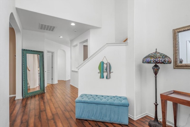 foyer entrance featuring dark wood finished floors, visible vents, arched walkways, and baseboards
