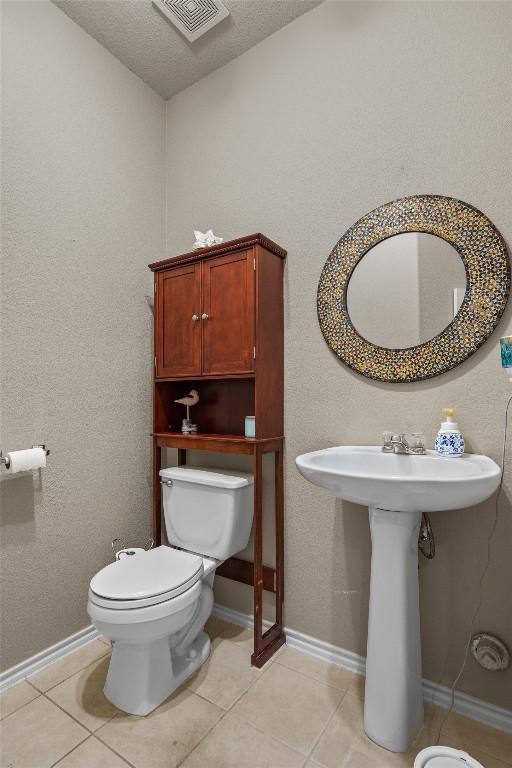 bathroom featuring visible vents, toilet, tile patterned flooring, and a sink