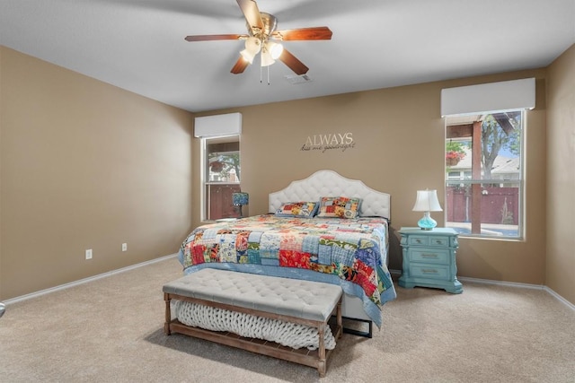 bedroom featuring light colored carpet, baseboards, a ceiling fan, and multiple windows
