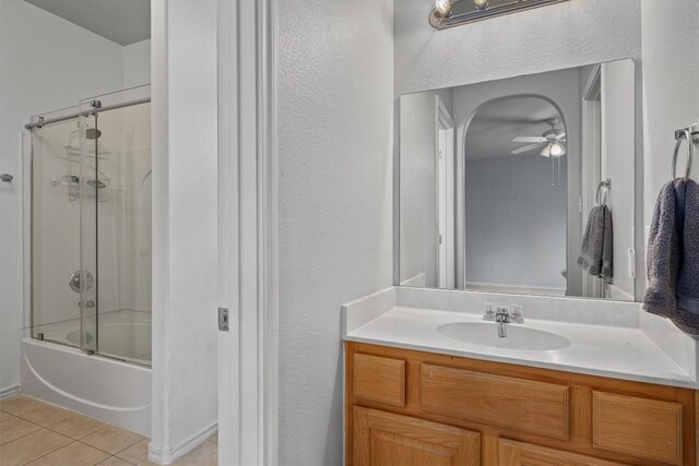 bathroom with vanity, ceiling fan, a textured wall, enclosed tub / shower combo, and tile patterned flooring