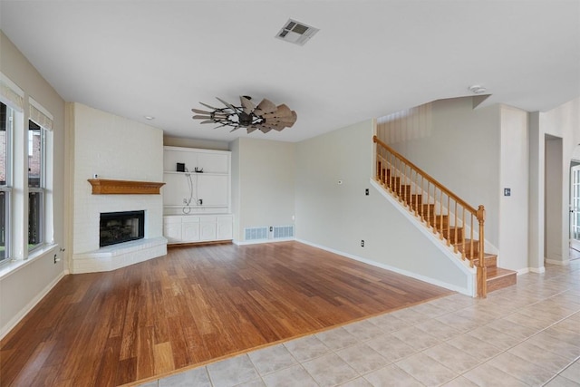 318 Ridge Run Dr, Georgetown, TX 78628 - unfurnished living room with stairway, light wood-type flooring, a fireplace, and plenty of natural light