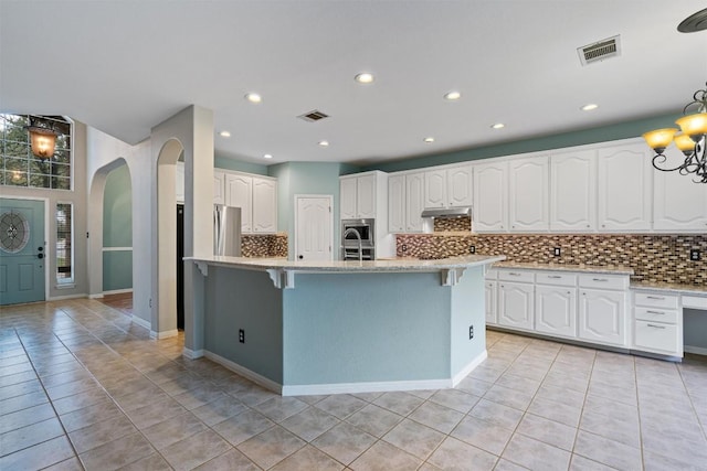 318 Ridge Run Dr, Georgetown, TX 78628 - kitchen featuring arched walkways, decorative backsplash, light tile patterned floors, and recessed lighting