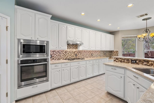 318 Ridge Run Dr, Georgetown, TX 78628 - kitchen with stainless steel appliances, under cabinet range hood, a chandelier, recessed lighting, and hanging light fixtures