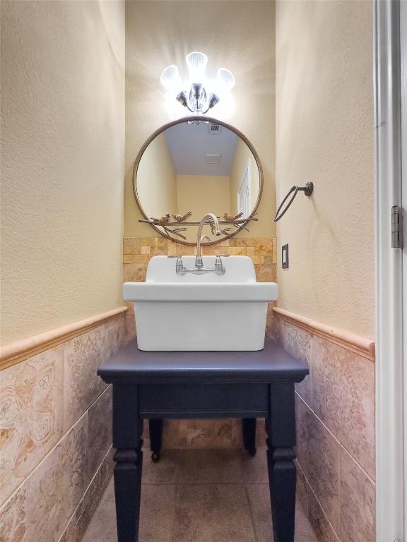 318 Ridge Run Dr, Georgetown, TX 78628 - bathroom with tile walls, a sink, wainscoting, and a textured wall