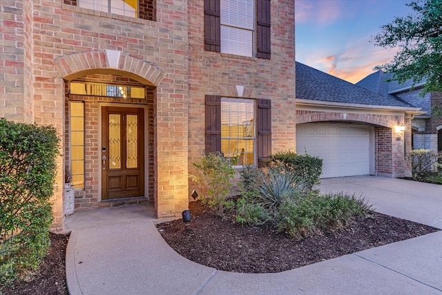431 Ridgetop Bnd, Cedar Park, TX 78613 - exterior entry at dusk with roof with shingles, brick siding, concrete driveway, and a garage