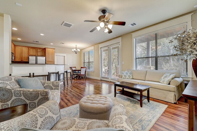 living area with recessed lighting, wood finished floors, visible vents, and ceiling fan with notable chandelier