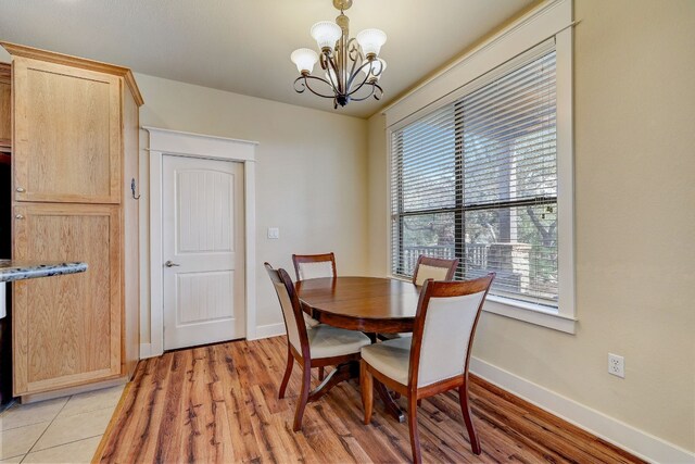 dining space featuring light wood finished floors, baseboards, and an inviting chandelier