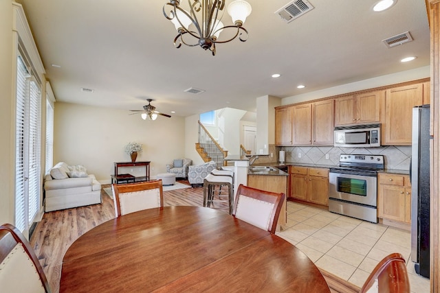 kitchen with dark countertops, backsplash, appliances with stainless steel finishes, and visible vents