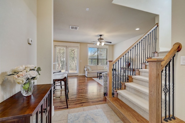 foyer entrance featuring visible vents, light tile patterned flooring, baseboards, stairs, and ceiling fan