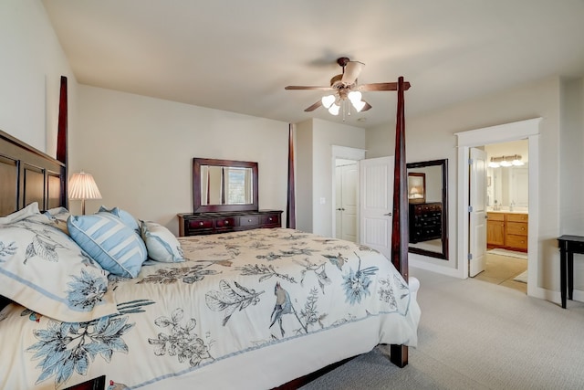 bedroom with ensuite bath, light carpet, and a ceiling fan