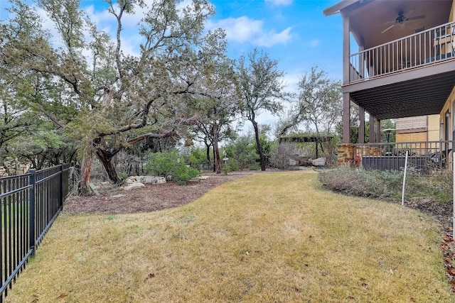 view of yard with a fenced backyard, a ceiling fan, and a balcony