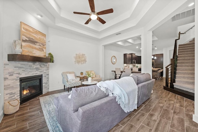 206 Olivia Dr Unit 120, Austin, TX 78738 - living area with a raised ceiling, stairway, a ceiling fan, wood finish floors, and a tile fireplace